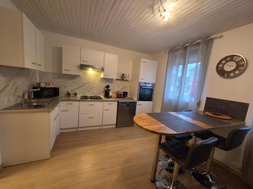 a kitchen with a table and a clock on the wall at Maison du bonheur in Montier-en-Der