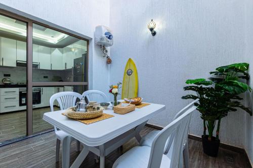 una sala da pranzo con un tavolo bianco e una tavola da surf di Maryam hospitality tamraght beach apartment ad Agadir