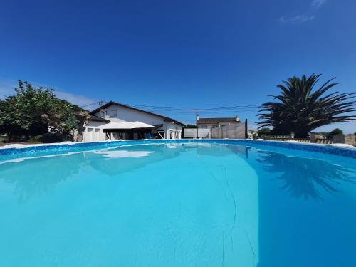 una gran piscina azul con una palmera en Villa Las Catedrales - Frente a la playa - Amplio jardín - Piscina, en Barreiros