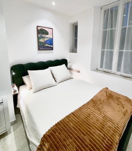 a bedroom with a white bed and a window at Apparemment cosy avec balcon plein centre de Cannes - Carla home in Cannes