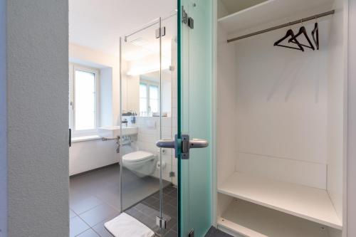 a bathroom with a toilet and a glass door at Hotel Ochsen in Uster