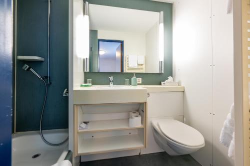 a bathroom with a sink and a toilet and a mirror at Hotel Ochsen in Uster