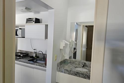 un bagno bianco con lavandino e specchio di Frente ao Parque da Lagoa Quente Entrada NÃO INCLUSA Aptos Particulares com varanda a Caldas Novas