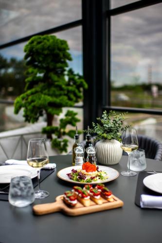 a table with a plate of food and glasses of wine at Premium Hotel, Novi Sad in Novi Sad