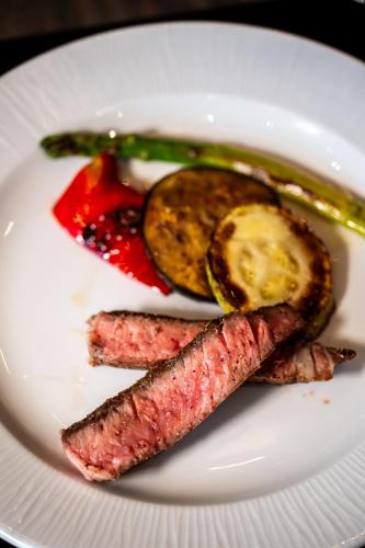 a white plate of food with meat and vegetables at Premium Hotel, Novi Sad in Novi Sad