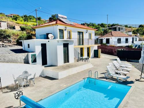a villa with a swimming pool and a house at Maria Cottage with Sea View in Estreito da Calheta