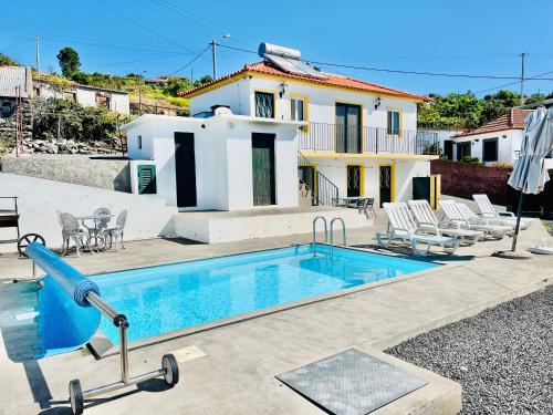 a pool with a slide in front of a house at Maria Cottage with Sea View in Estreito da Calheta