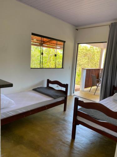 a bedroom with two beds and a large window at Hospedagem Olhos d'Água in Alto Paraíso de Goiás