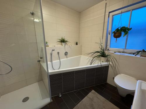 a bathroom with a tub and a toilet and a sink at Alpen Apartman Freilassing in Freilassing