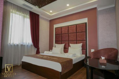 a bedroom with a large bed and a desk at Viagio hoteL in Yerevan