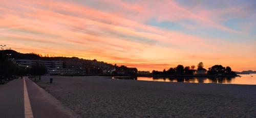 a sunset over a beach with a body of water at Camiño do Mar in Baiona