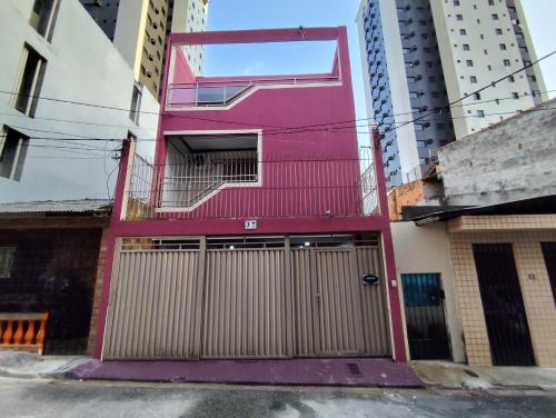 a pink building with a gate in front of some buildings at Casa com suítes privativas - Localização no centro, perto de serviços e pontos turísticos in Belém
