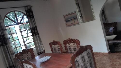 a dining room with a table and chairs and a window at Afonta's Greenhouse Retreat in Daranka