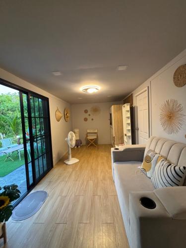 a living room with a couch and a large window at Cana Garden House 1 โฮมสเตย์ in Ban Khok