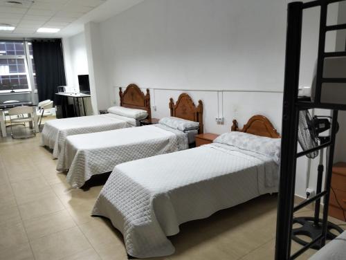 a room with four beds with white sheets on them at Gadir in Cádiz
