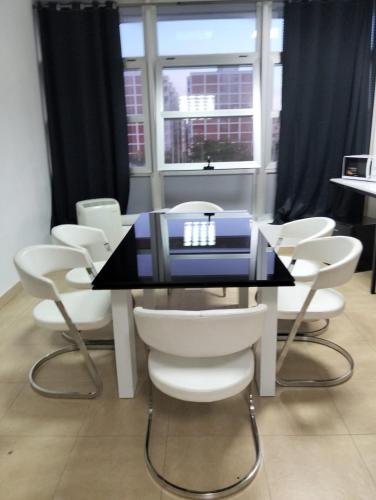 a table with white chairs and a blue suitcase on it at Gadir in Cádiz