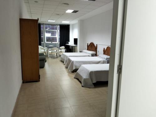 a room with three beds and a table and chairs at Gadir in Cádiz