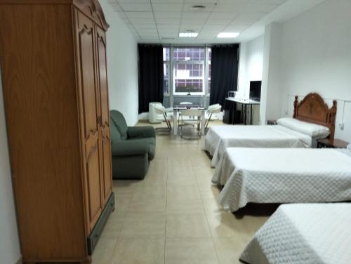 a hotel room with three beds and a table and chairs at Gadir in Cádiz