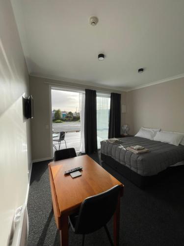 a bedroom with a bed and a desk and a table at Empire Cafe & Accommodation in Kumara