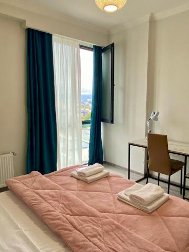 une chambre avec un grand lit avec un bureau et une fenêtre dans l'établissement Sweet Apartment For Daily Rent, à Tbilissi
