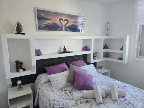 a bedroom with a bed with purple and white pillows at Medano Time in El Médano