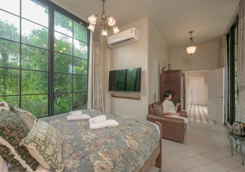 a man sitting in a chair in a bedroom with a bed at VANA Homestay in Ban Tai