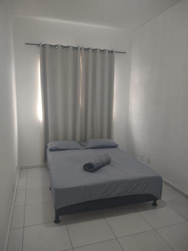 a bed in a white room with a curtain at Casa com 03 Quartos, Piscina e Churrasqueira em Itaipuaçu Maricá RJ in Maricá