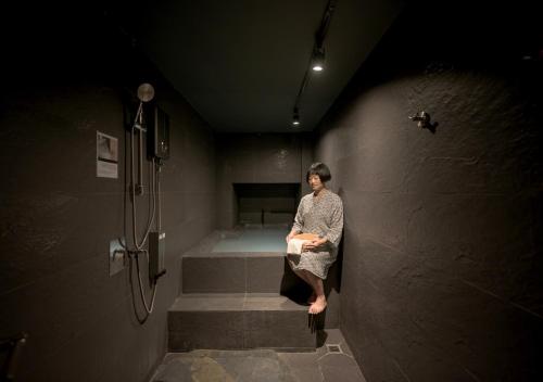a woman is sitting on the stairs in a bathroom at VANA Homestay in Ban Tai