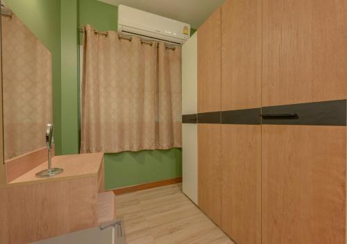a bathroom with green walls and a wooden cabinet at VANA Homestay in Ban Tai