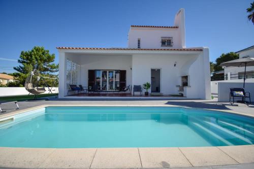 a villa with a swimming pool in front of a house at Marisol Village in Corroios