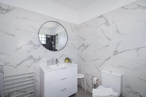 a white bathroom with a sink and a mirror at Marisol Village in Corroios