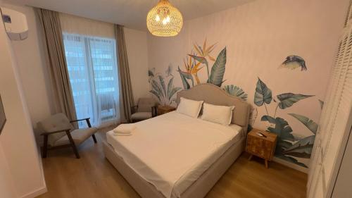 ein Schlafzimmer mit einem Bett mit einem Pflanzenwandbild an der Wand in der Unterkunft Velora Apartments in Năvodari