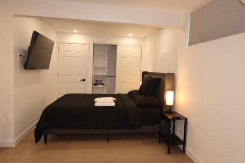 a bedroom with a black bed and a flat screen tv at 2 bedrooms near Downtown, Airport, stadiums, light rail in Seattle
