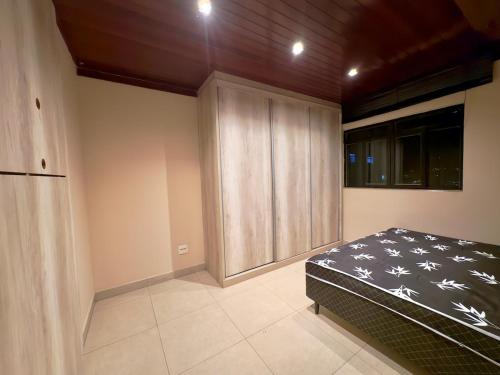 a bedroom with a bed and a wooden cabinet at Cobertura Jacuzzi e Area Gourmet Sao Judas in Divinópolis