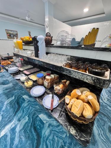 a buffet with bread and pastries and a pool of food at JV Pousada in Paraty