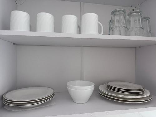 a white shelf with plates and cups and dishes at Apartment in Ploiești 3 in Ploieşti