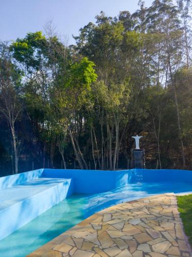 a blue swimming pool with trees in the background at Pousada Moinho de Pedra in Extrema