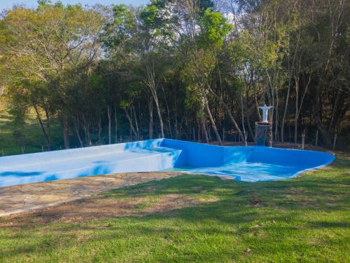 a blue pool in a yard with trees in the background at Pousada Moinho de Pedra in Extrema
