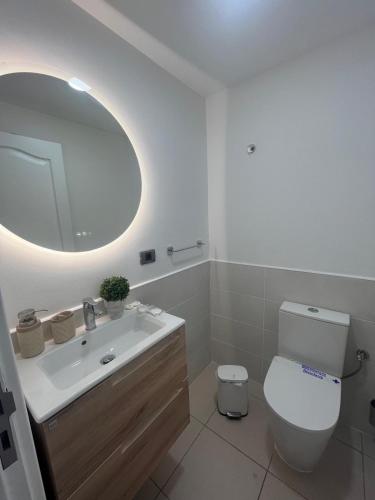 a bathroom with a sink and a toilet and a mirror at Hola La Fuente in Puerto de Mogán