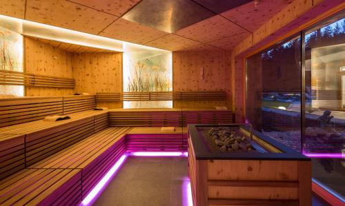 a sauna with a hot tub with purple lights at Hotel Weiher Green Lake in Falzes