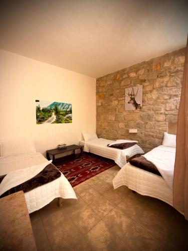 a bedroom with three beds and a stone wall at Dana Gardens Hotel in Dana