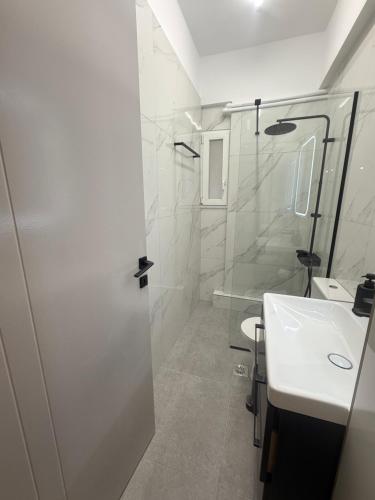 a white bathroom with a shower and a sink at Domus Philippi in Larisa