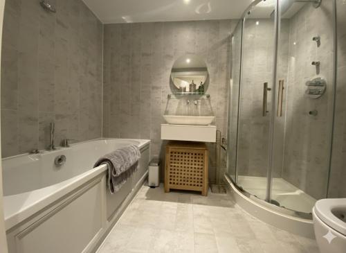a bathroom with a tub and a sink and a shower at Apartment Lux Stratford London in London