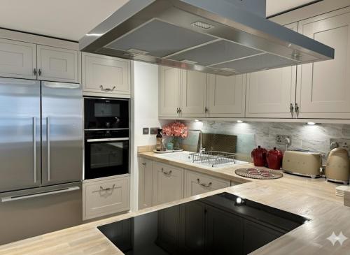 a kitchen with white cabinets and a stainless steel refrigerator at Apartment Lux Stratford London in London