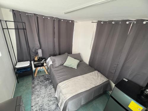 a small bed in a room with gray curtains at La Casona Xalapa, céntrica y lugar muy tranquilo in Xalapa
