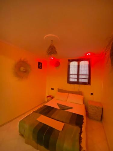 a bedroom with orange walls and a bed with red lights at Bright Wave Surfhouse in Tamraght Ouzdar