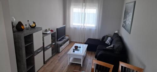 a living room with a black couch and a table at Casa da Caroxinha in Quinta do Conde