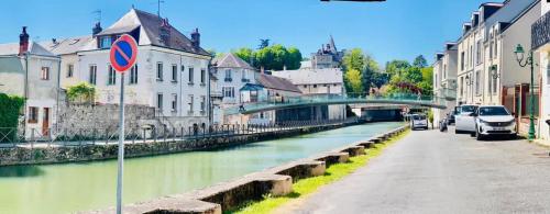 a river in a city with cars parked next to buildings at Escale Secrète Détente Montargis Parking Gratuit in Montargis
