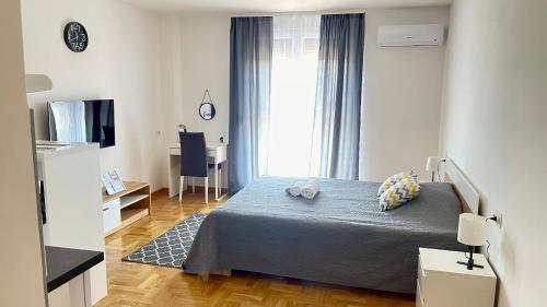 a bedroom with a bed and a desk and a window at Riverside Nis in Niš