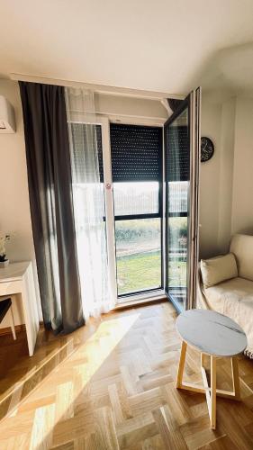 a living room with a table and a large window at Riverside Nis in Niš